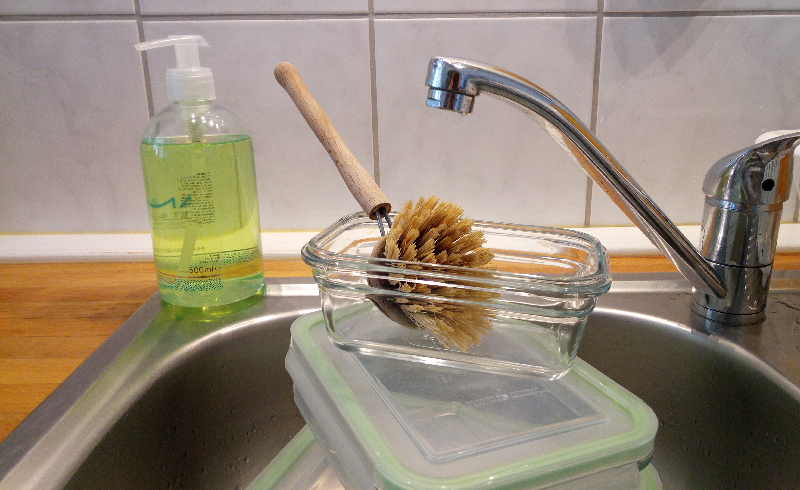 Küchenspülbecken mit Glasdosen, einer Spülbürste und Spülmittel