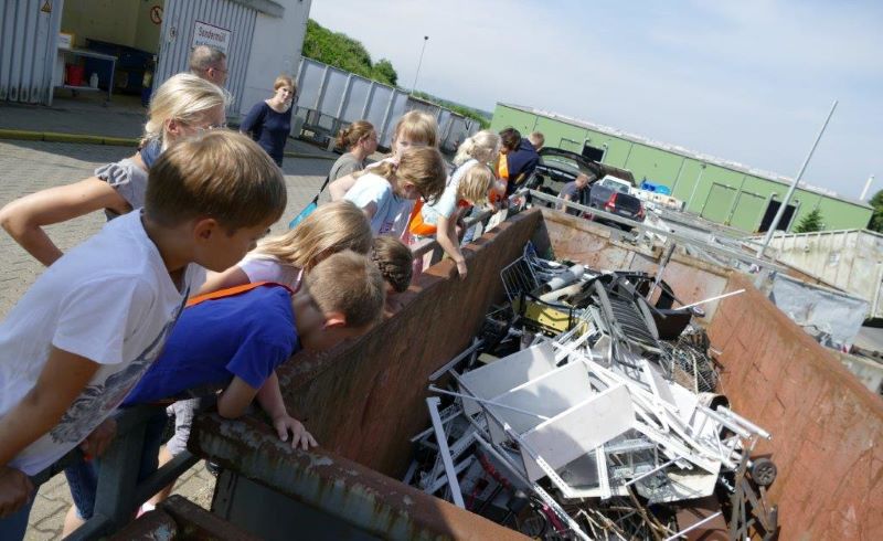 Eine Gruppe Kinder steht an einem Container mit Metallabfällen und schaut hinein