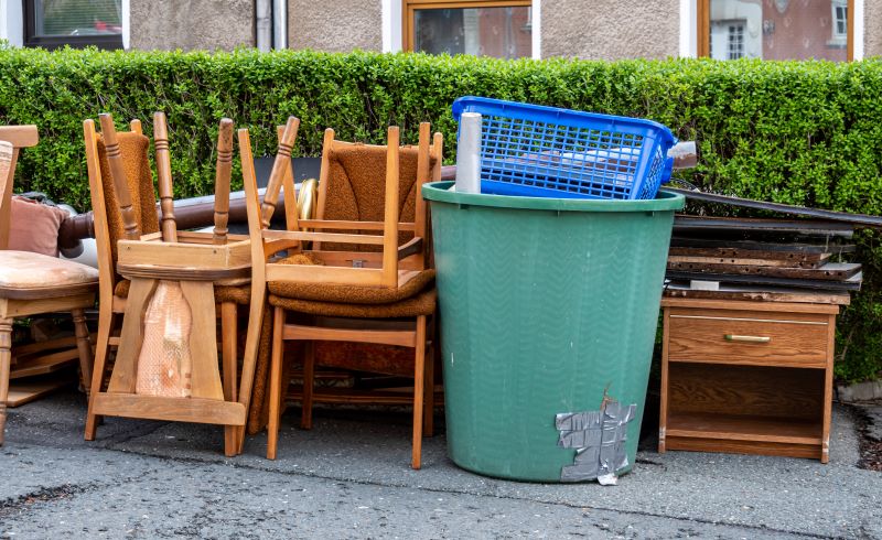 Sperrmüll (Möbel, Kunststofftonne, Kinderspielküche) steht vor einer Hecke